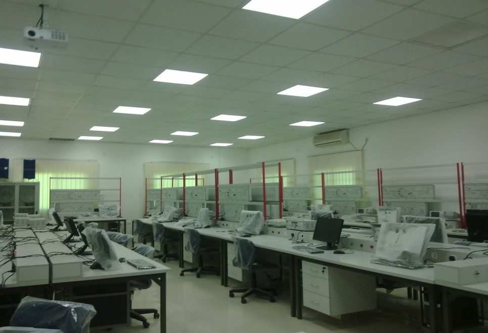 A spacious, empty computer lab with covered desks, monitors, and bright overhead lights.